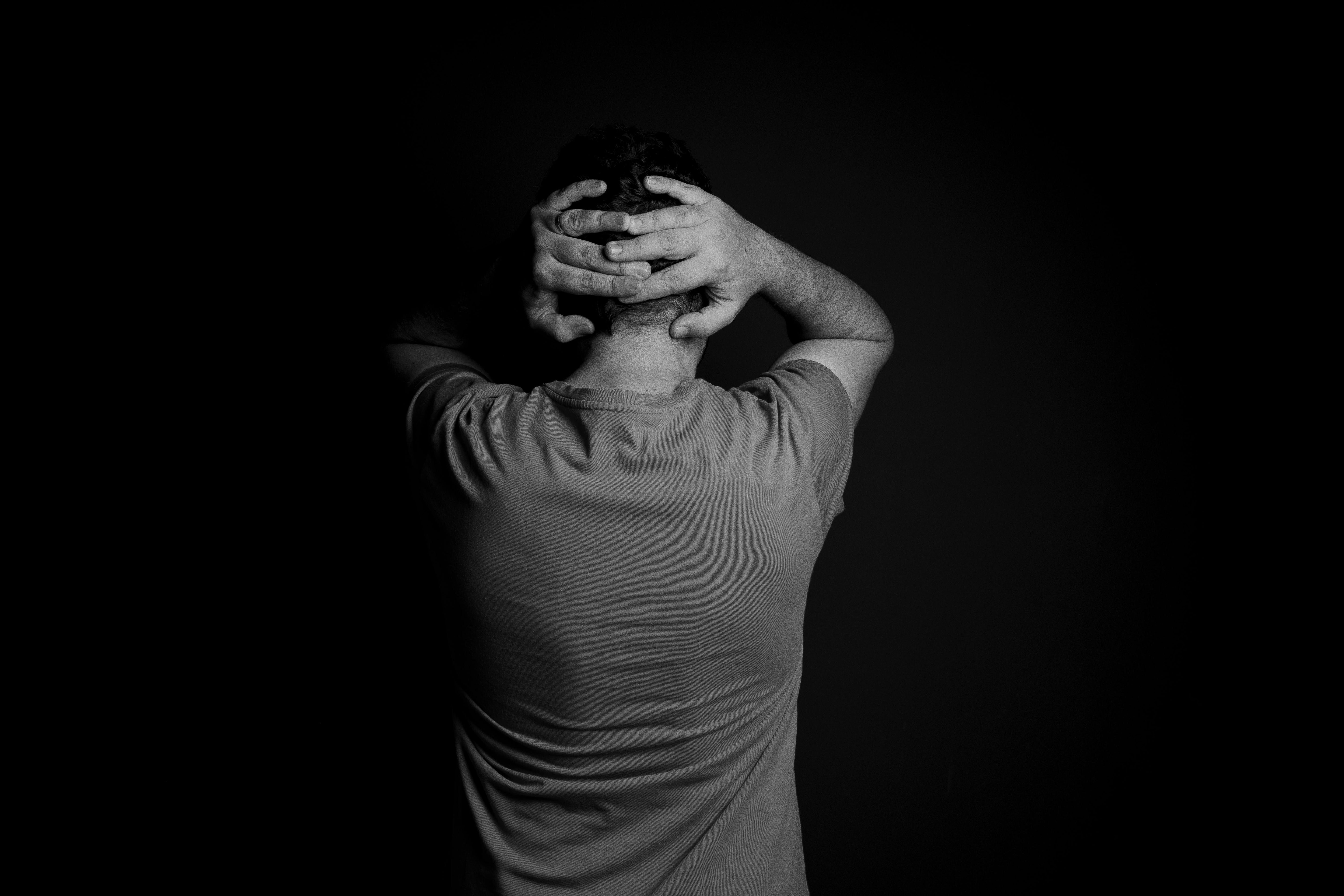 Man standing with hands behind his head, conveying the silent stress of sperm count and male fertility concerns