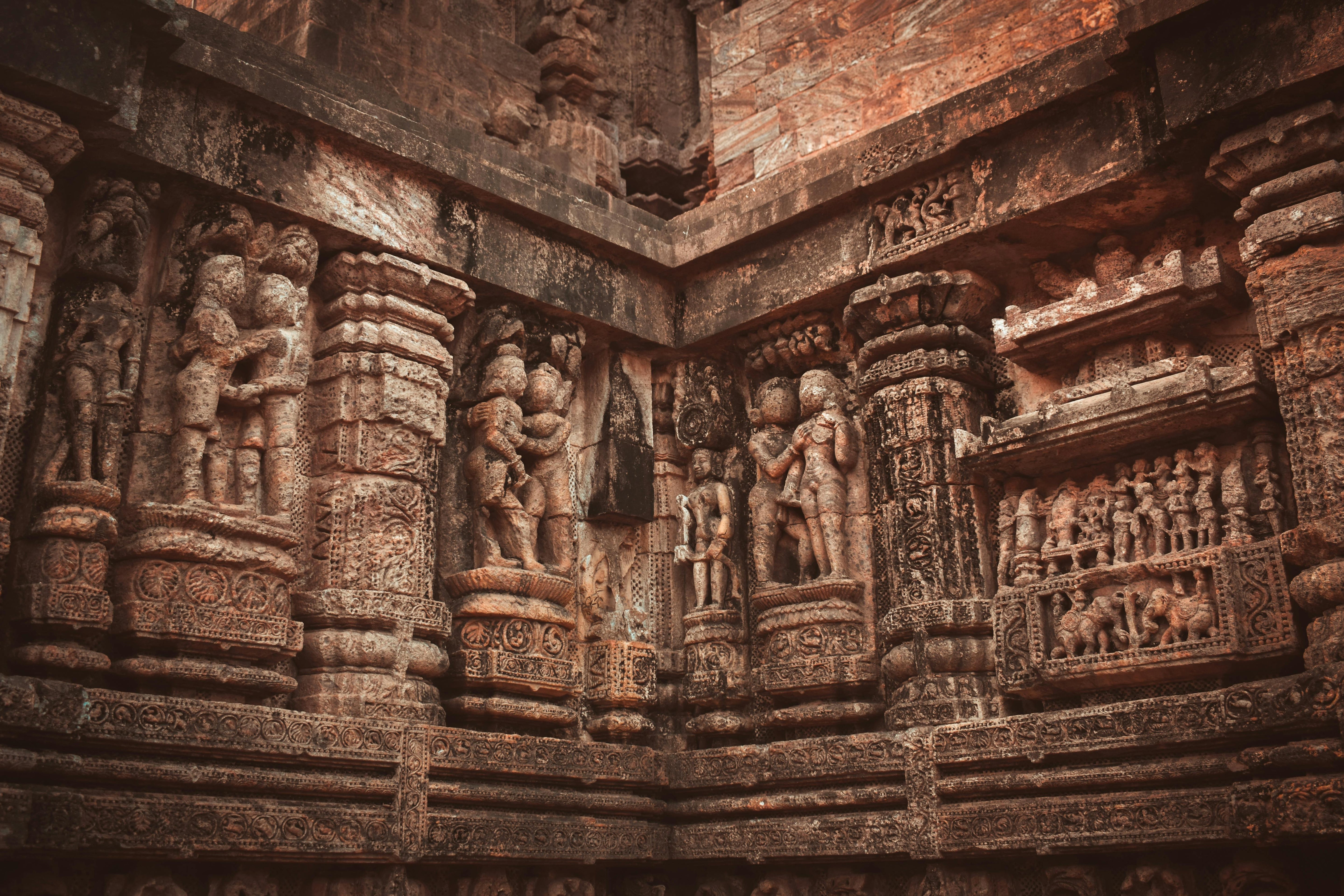 Ancient erotic stone carvings on the walls of an Indian temple, depicting intimate figures, representing the cultural roots of the Kamasutra