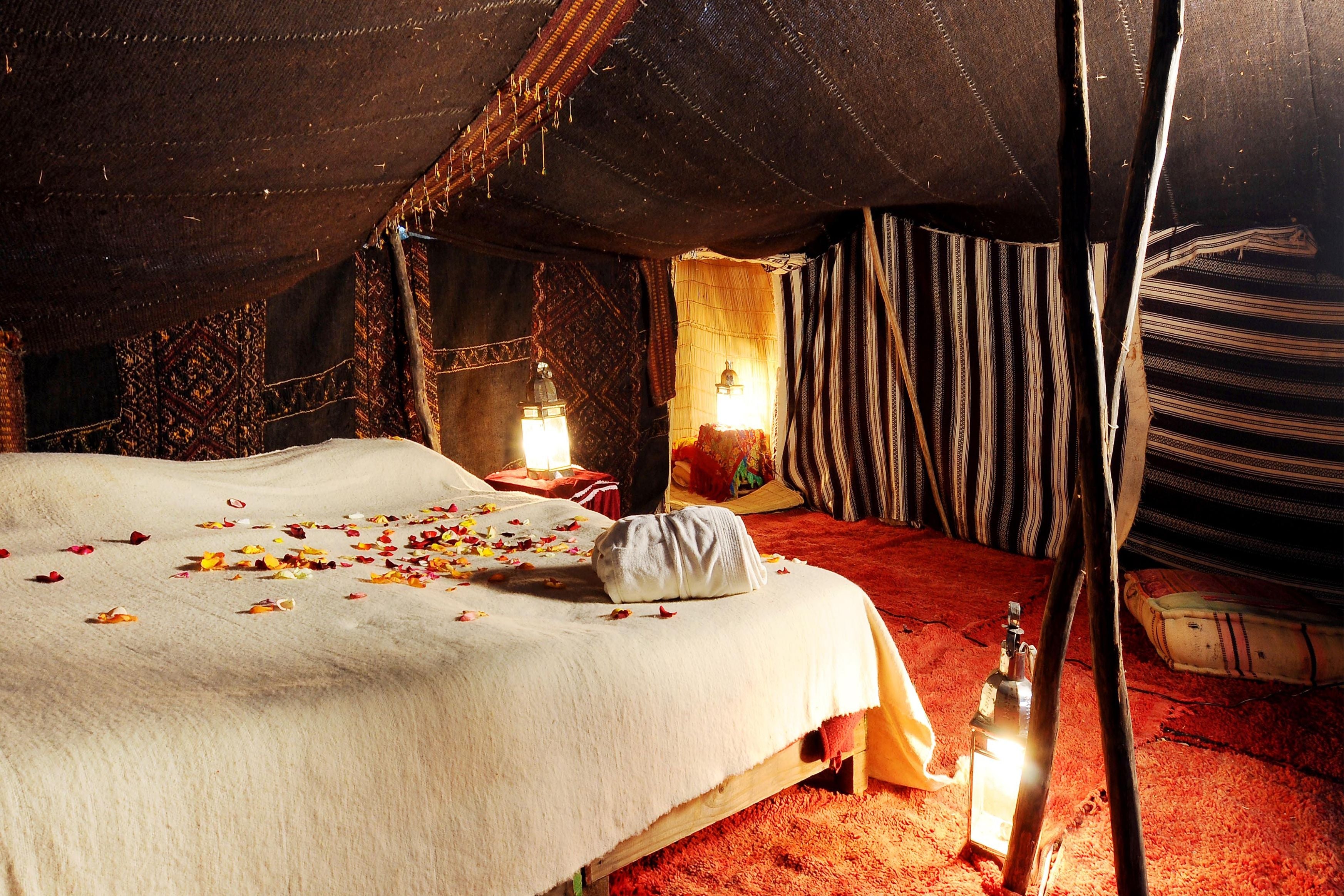 Warm candlelit room scattered with rose petals on the bed, the kind of intimate setting prepared for a couples magasm
